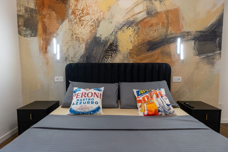 Camera matrimoniale dell'appartamento Bulldog Home Bergamo con letto blu notte e parete astratta