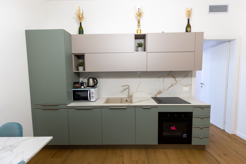 Cucina dell'appartamento Champagnerie con piano in finto marmo e ante verde salvia